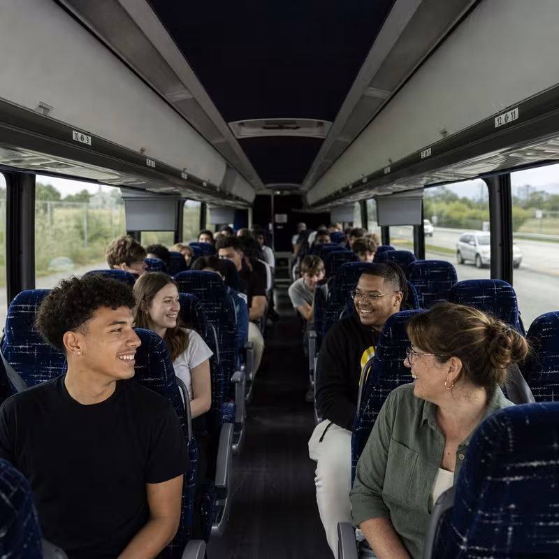 Group boarding a white charter bus for School Transportation transportation in Greensboro