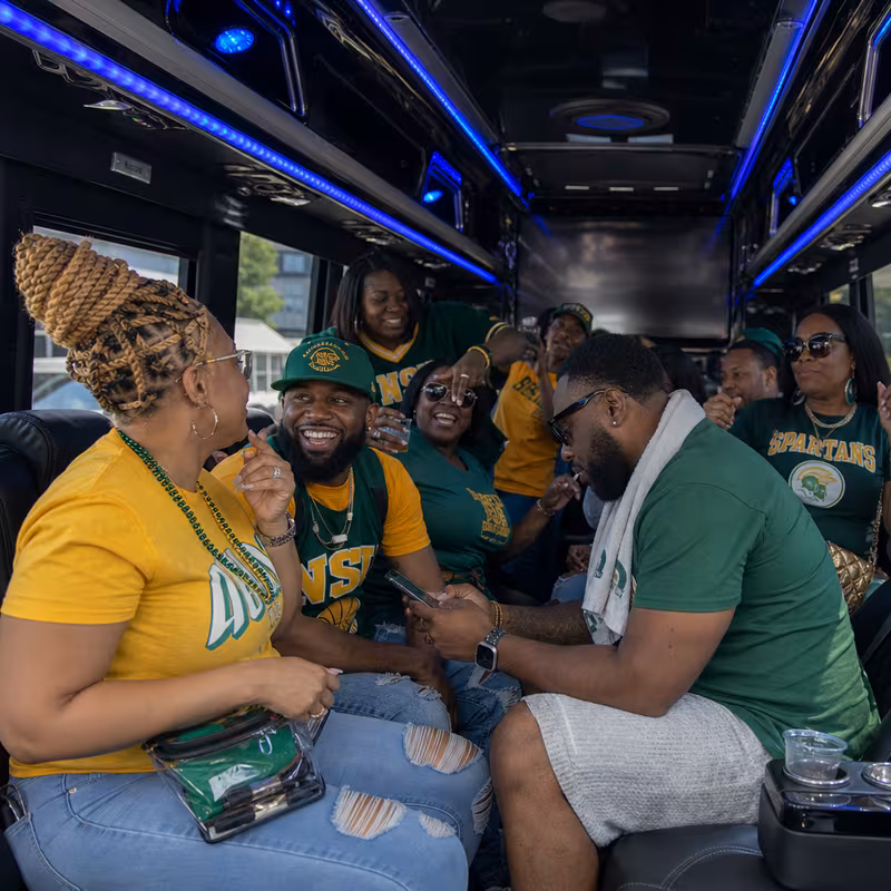 Group boarding a white charter bus for Sporting Event Transportation transportation in Greensboro